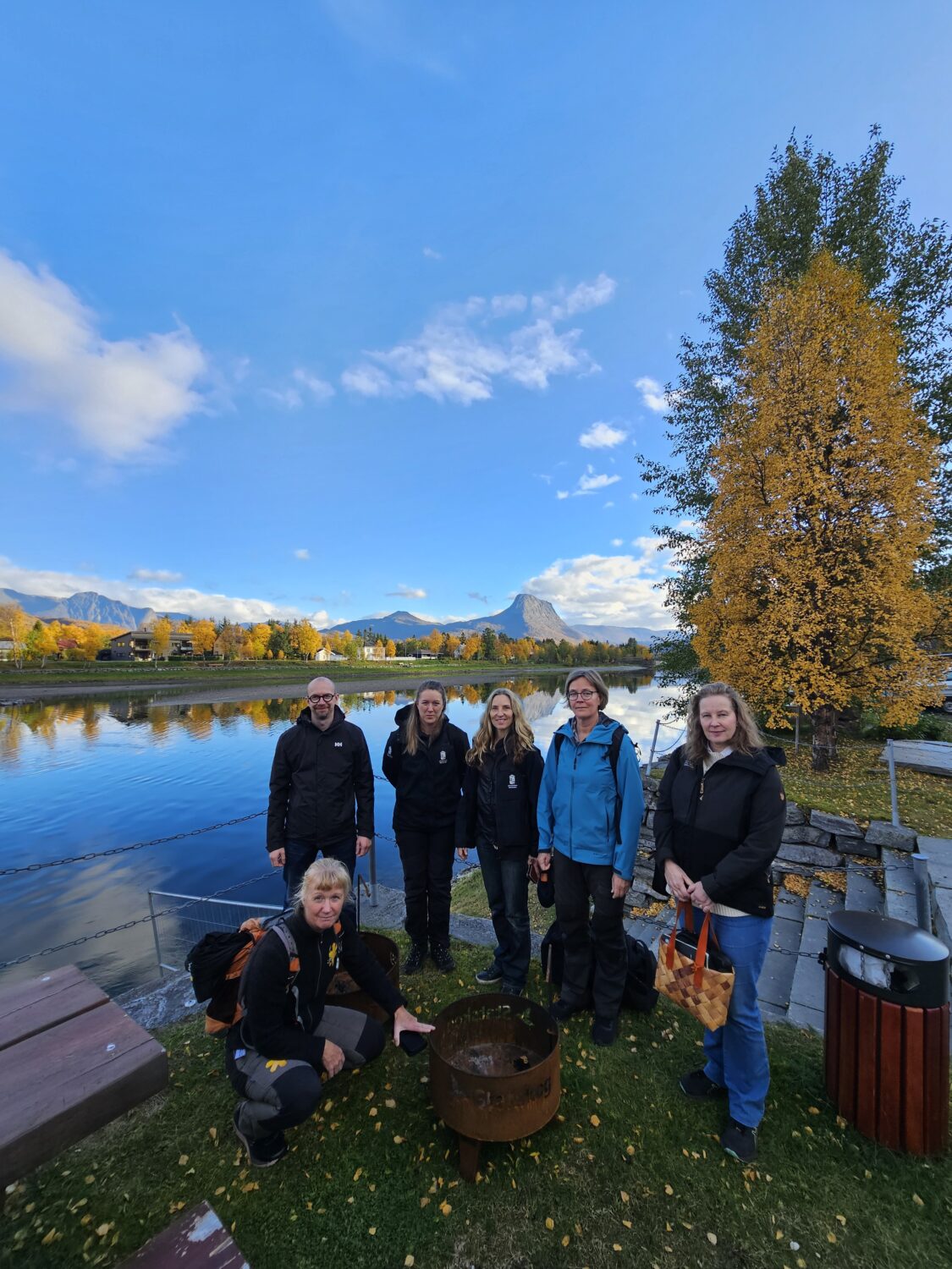 Gruppe mennesker forran en elv i høstlandskap