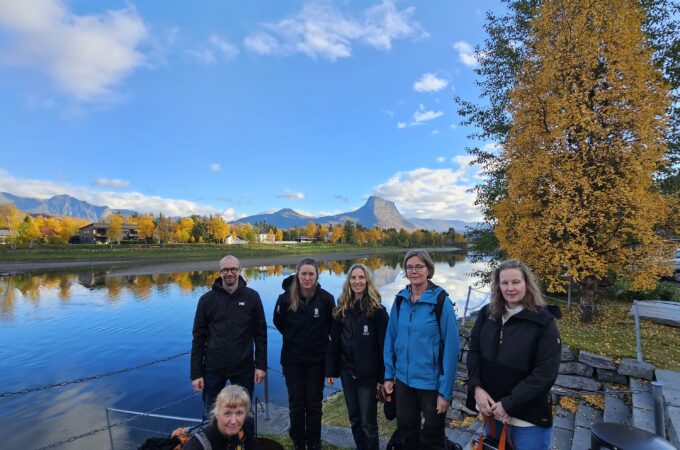 Gruppe mennesker forran en elv i høstlandskap